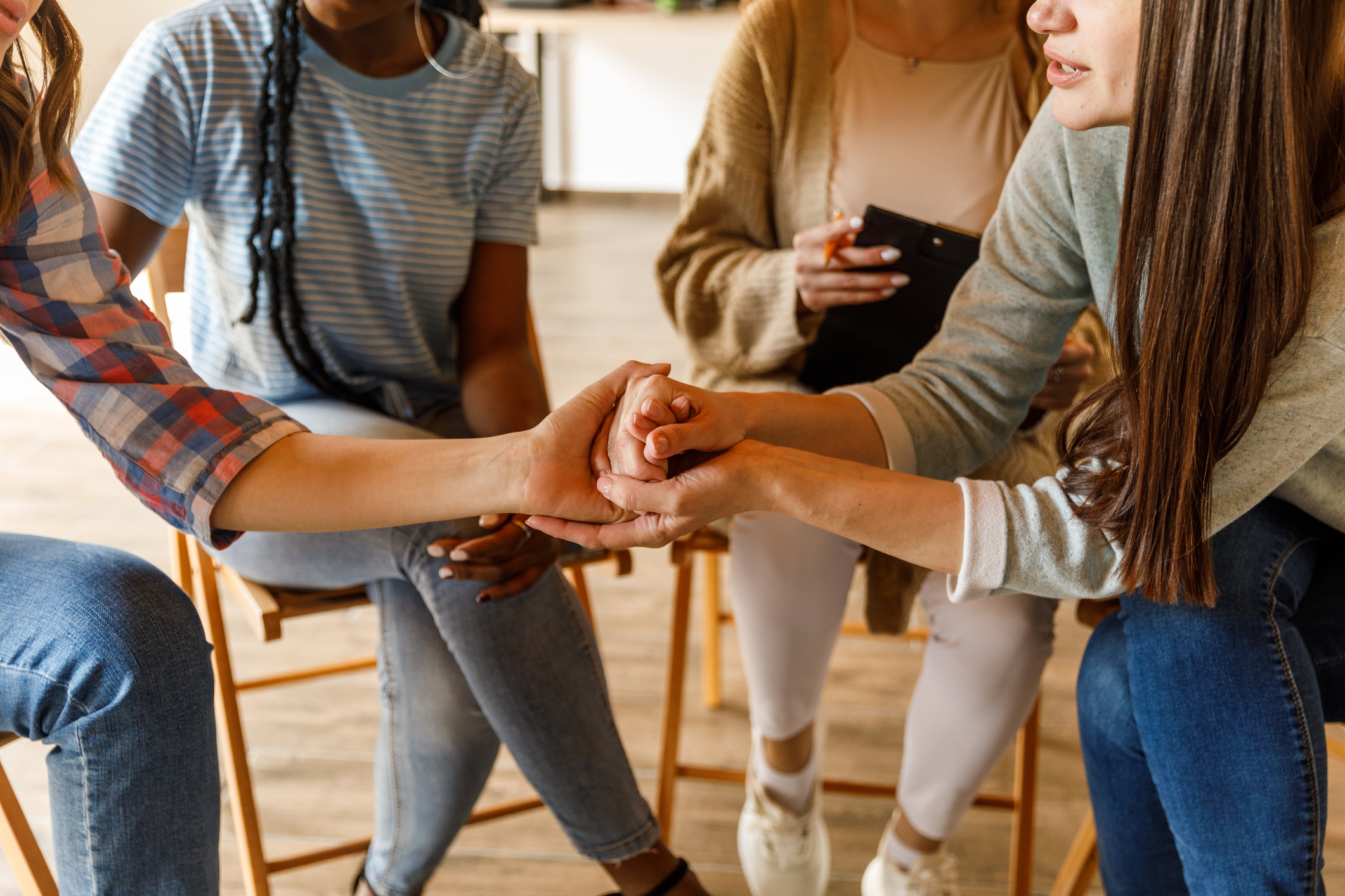Holding hands with a young woman to show support during a group therapy session BCARA Current Regular Reading